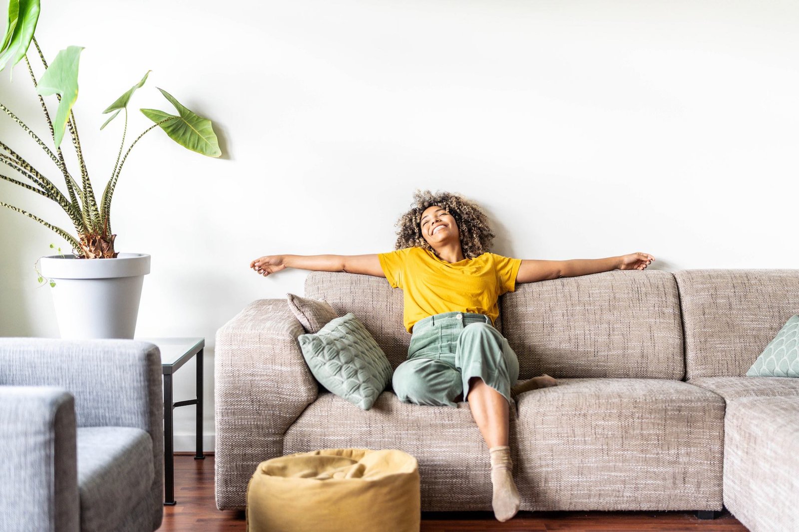 Happy afro american woman relaxing on the sofa at home - Smiling girl enjoying day off lying on the couch - Healthy life style, good vibes people and new home concept